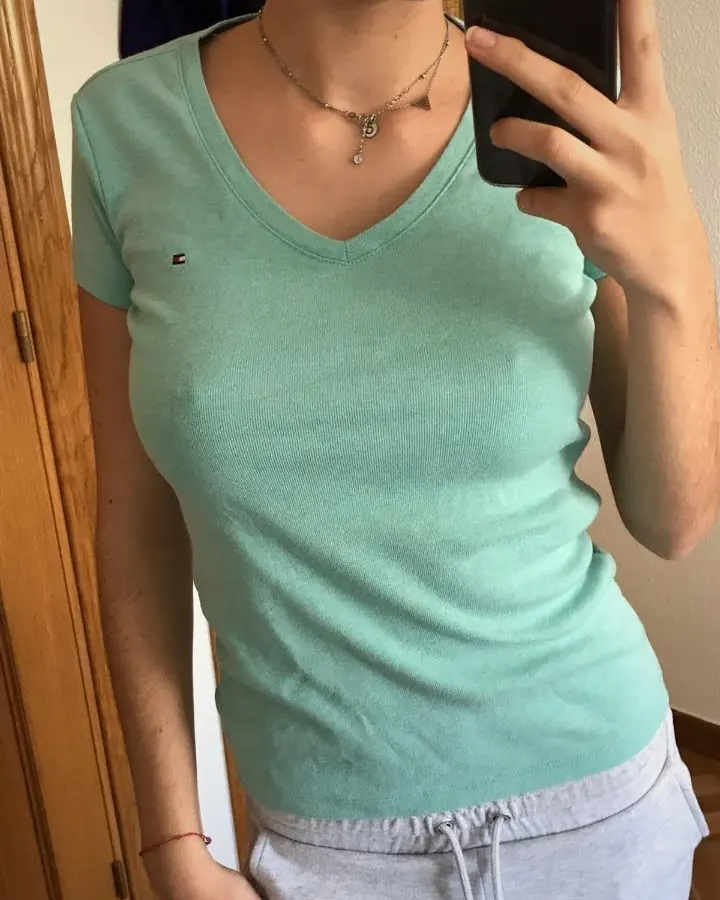 Femme jeune en t-shirt vert, sweat gris, collier, sourire, photo miroir