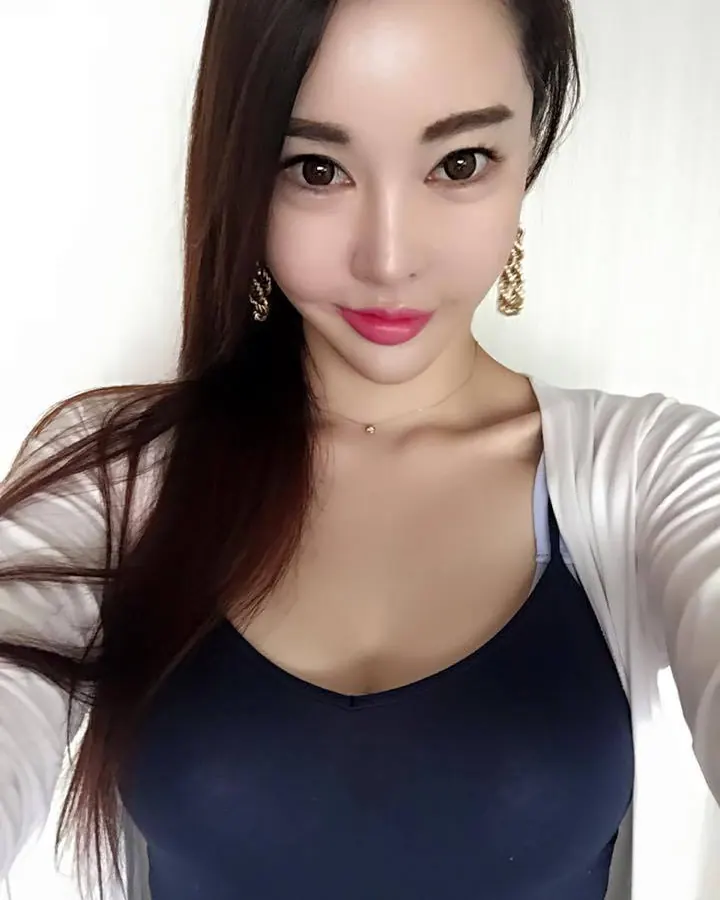 Femme aux cheveux chatain en haut bleu foncé et cardigan blanc, vue de face