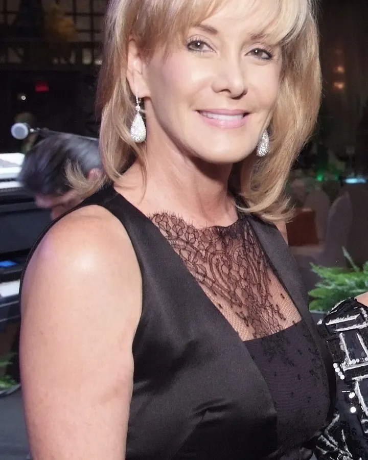 Femme blonde souriante, robe noire dentelle, scène de spectacle