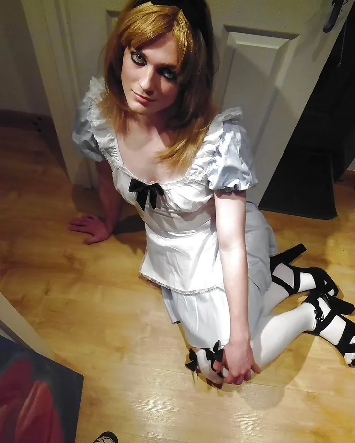 Femme aux cheveux roux, en haut noir, prenant un selfie dans une salle de bain.