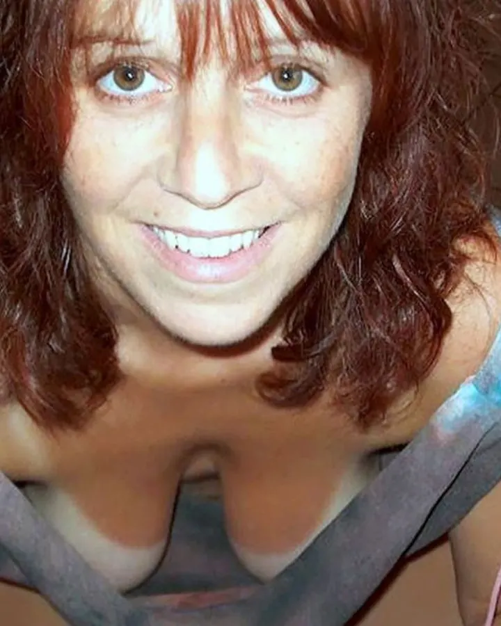 Femme aux cheveux roux, en robe noire, posant dans un cadre intérieur avec une expression neutre.
