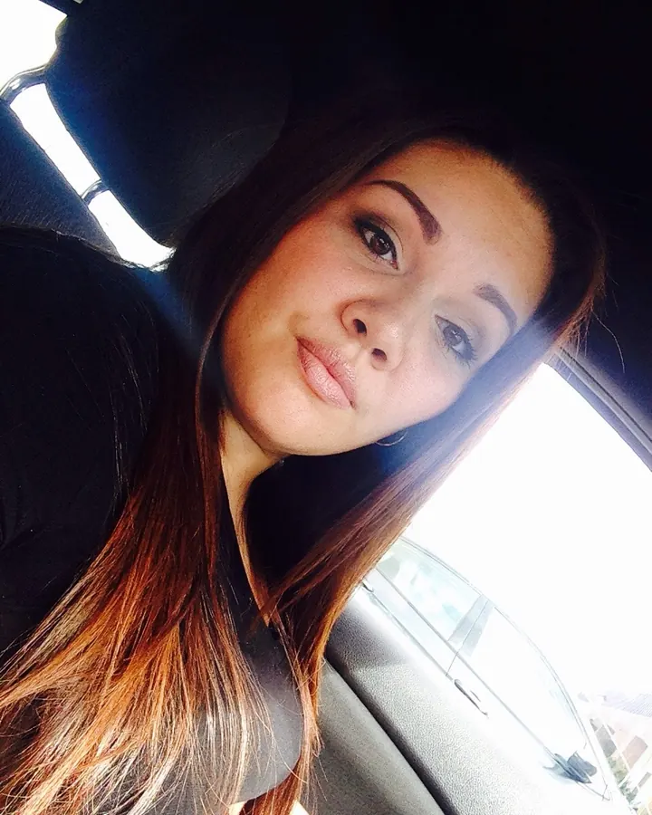 Femme européenne en tenue sombre, prend un selfie dans une voiture.