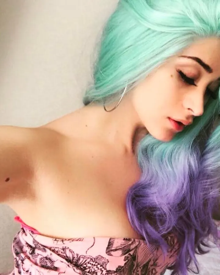 Jeune femme aux cheveux turquoise et violets, regard baissé