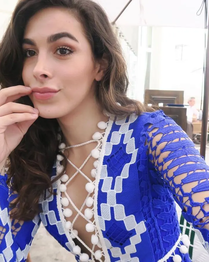 Femme aux cheveux bruns en haut bleu, posant dehors