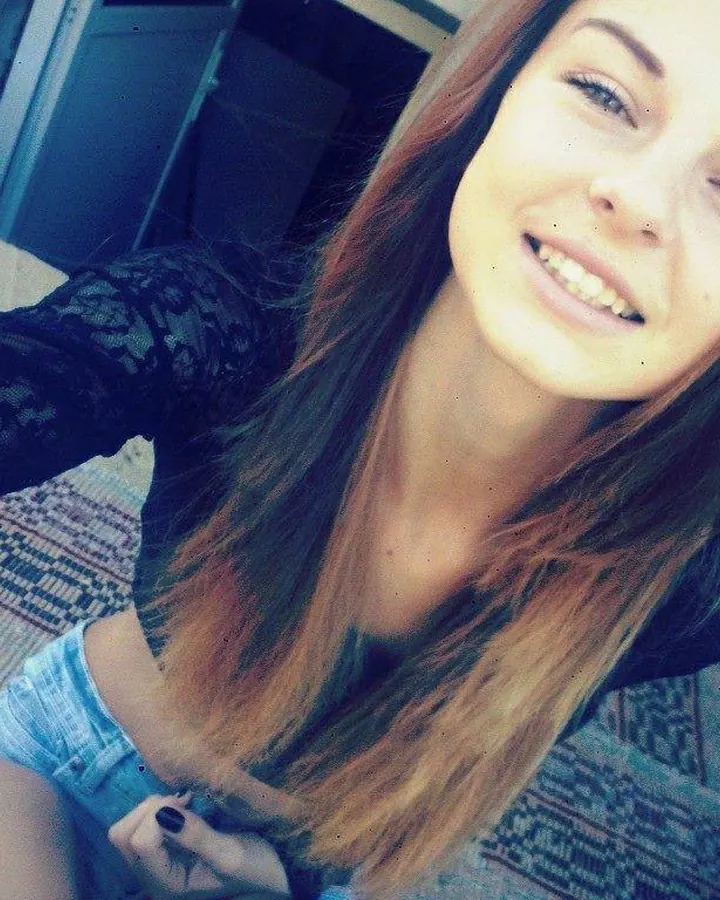 Femme aux cheveux bruns portant un haut noir, regardant directement l'appareil photo contre un fond blanc.